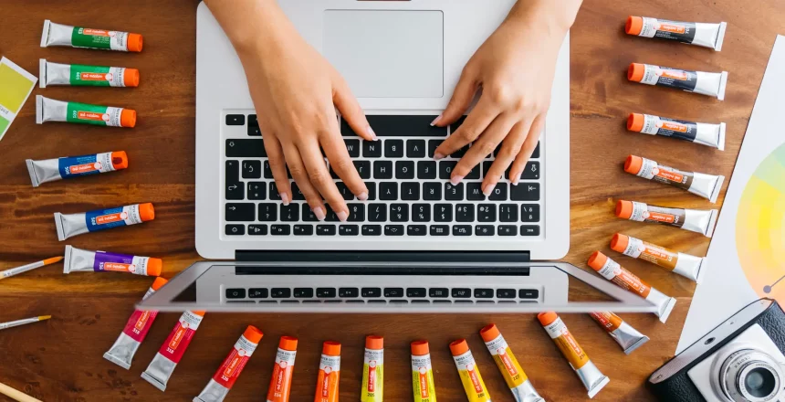 graphiste-a-l-ordinateur-portable-avec-des-tubes-de-peinture